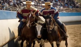 Two huaso horsemen on criollo horses pressing a steer against the inner wall of a media luna arena during Chilean rodeo